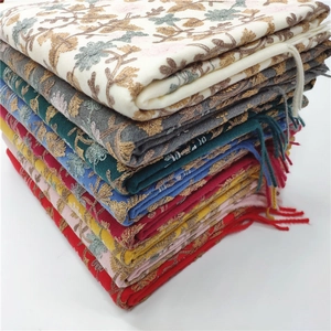 Detailed stack of multi-colored embroidered cashmere scarves featuring fringe tassels