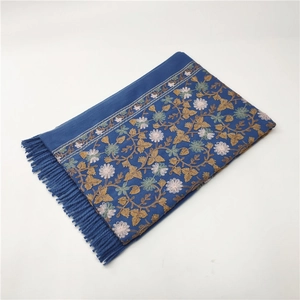 Detail of blue pashmina scarf featuring golden floral embroidery and fringed tassels