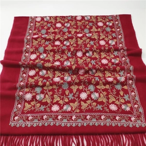 Detail of red faux cashmere scarf with intricate floral embroidery and tassel fringe edges