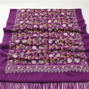 Detailed close-up of purple cashmere-like scarf with intricate floral embroidery and tassels