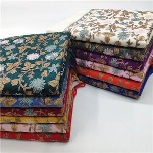Detailed view of neatly folded scarves featuring intricate floral embroidery and fringes