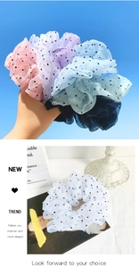 Close-up of five colorful polka dot organza hair scrunchies held against a blue sky