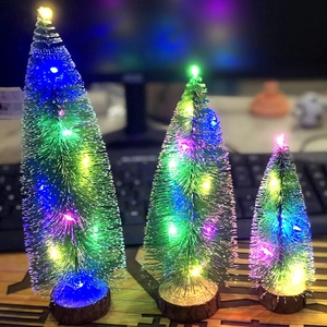 Three mini green Christmas trees with colorful LED lights on round wooden bases