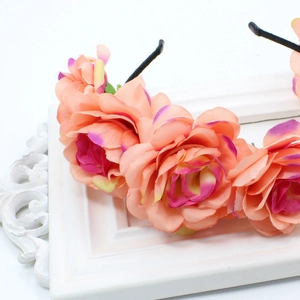 Detailed view of peach fabric roses with purple edges on a floral headband accessory