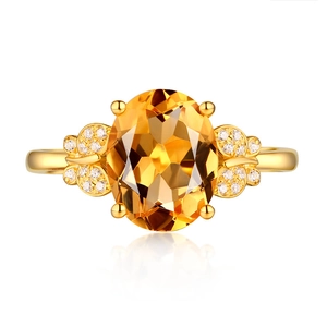 Close-up of golden ring with oval yellow gemstone and delicate diamond butterfly accents