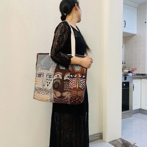 Canvas tote bag with artistic cat patterns and beige shoulder straps shown by a model