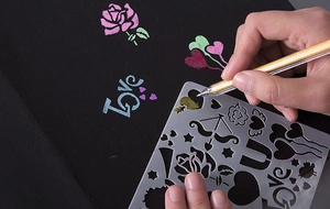 Macro view of metallic gel pens drawing gold and pink patterns on black DIY album pages