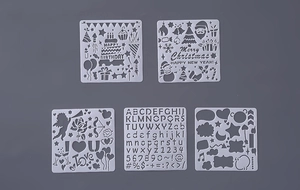 Five white translucent PET drawing stencils with holiday greetings and alphabet patterns