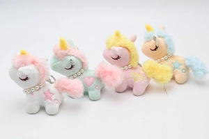 Detail of four colorful plush unicorn keychains with pearl necklaces and embroidered icons