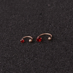 Macro shot of stainless steel nose rings with red cubic zirconia on black texture
