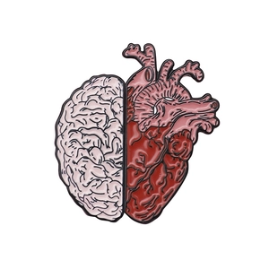 Detail of anatomical heart and brain enamel pin with polished black metal outlines