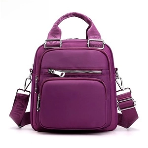 Detail of purple canvas shoulder bag featuring front zipper pockets and adjustable straps