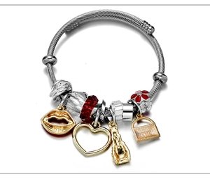 Detail of adjustable silver wire bracelet with gold charms, red flowers and crystals