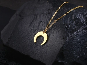 Golden crescent moon necklace pendant displayed on a dark textured rock background