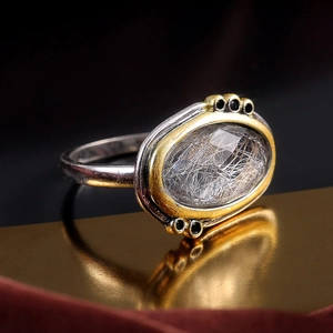 Vue latérale macro d'une bague rétro sertie d'un quartz rutilé avec détails noirs