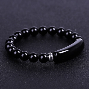 Macro shot of black beaded bracelet featuring a sleek curved bar and silver metal spacer