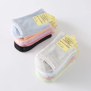 Colorful set of cotton mid-tube socks in candy colors with paper tags on gray background