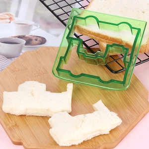 Detailed view of green puppy-shaped sandwich cutter with finished toast crusts on a board