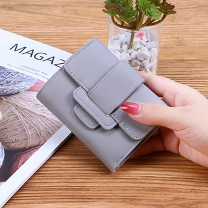 Chic grey PU leather tri-fold short wallet held over a wooden desk with a minimalist style