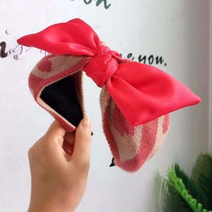 Detailed view of a fashionable knitted wide headband with a large red satin bow tie