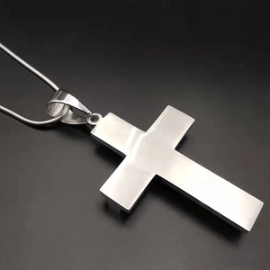 Macro shot of silver stainless steel cross pendant and snake chain on a black background