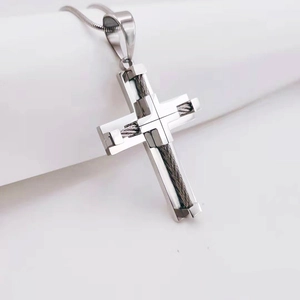 Macro shot of silver stainless steel cross pendant with black wire wrap and snake chain