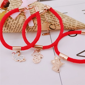 Detail of red braided zodiac rat bracelet with gold pendant and sparkling zircon