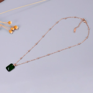 Detail of rose gold necklace with emerald-cut green zircon and K18 hallmark stamp