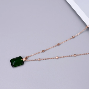 Detailed view of emerald cut green gemstone pendant with rose gold beaded chain necklace