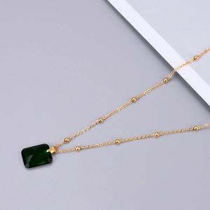 Rose gold emerald green zircon pendant necklace with beaded chain on a gray background