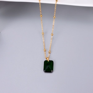 Emerald-cut green zircon pendant on a rose gold satellite chain against a gray background