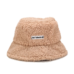 Vue détaillée du bob en peluche beige avec patch brodé de lettres blanches sur le devant