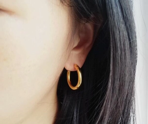 Close-up of a model wearing minimalist golden hoop earrings with a polished finish