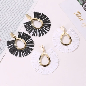 Detail view of bohemian fan-shaped tassel earrings in black and white with gold finish