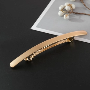 Detail of matte gold metal hair clip showing brushed texture and spring automatic buckle