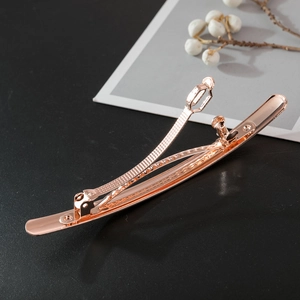 Detailed view of polished rose gold spring hair clip with mirror finish on dark backdrop