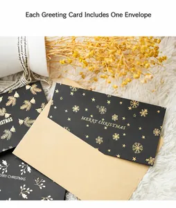 Close-up of black gold foil Christmas card with envelope and warm decorative elements