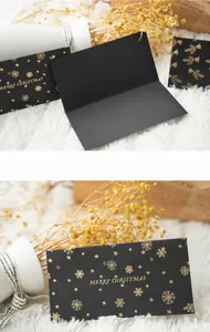 Detail of black greeting card with gold foil Merry Christmas text and star patterns