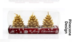 Three golden pinecone-shaped Christmas candles in a clear box with festive red base