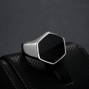 Mens silver stainless steel ring with hexagonal black inlay on a textured display