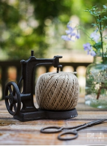 Detail of vintage cast iron sewing machine string holder with scissors in garden
