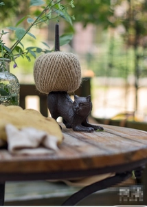 Detail of vintage cast iron cat twine holder with jute rope ball on a rustic garden table