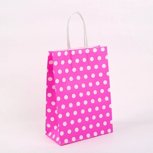 Vue détaillée du sac cadeau en papier kraft rose avec pois blancs et anses torsadées