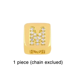 Macro shot of gold-plated letter M dice charm with sparkling zircon stone inlay