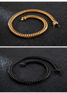 Detail of gold and black thick Cuban link necklaces with stone-set lobster clasps on dark surface