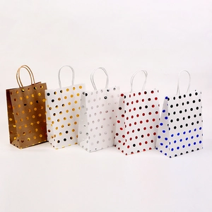 Macro detail of kraft paper gift bags with metallic foil polka dots and rope handles