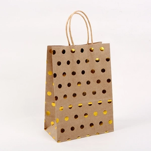Detail of kraft paper gift bag featuring gold foil polka dots and reinforced paper handle