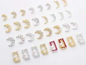 Detailed close-up of metallic moon nail art charms with pearls and sparkling rhinestones