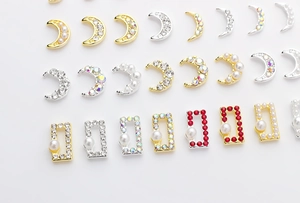 Detailed view of crescent moon and rectangle gold nail charms with pearls and rhinestones
