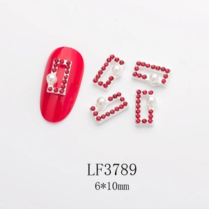 Macro view of rectangular nail charms with red rhinestones and pearls on a long red nail